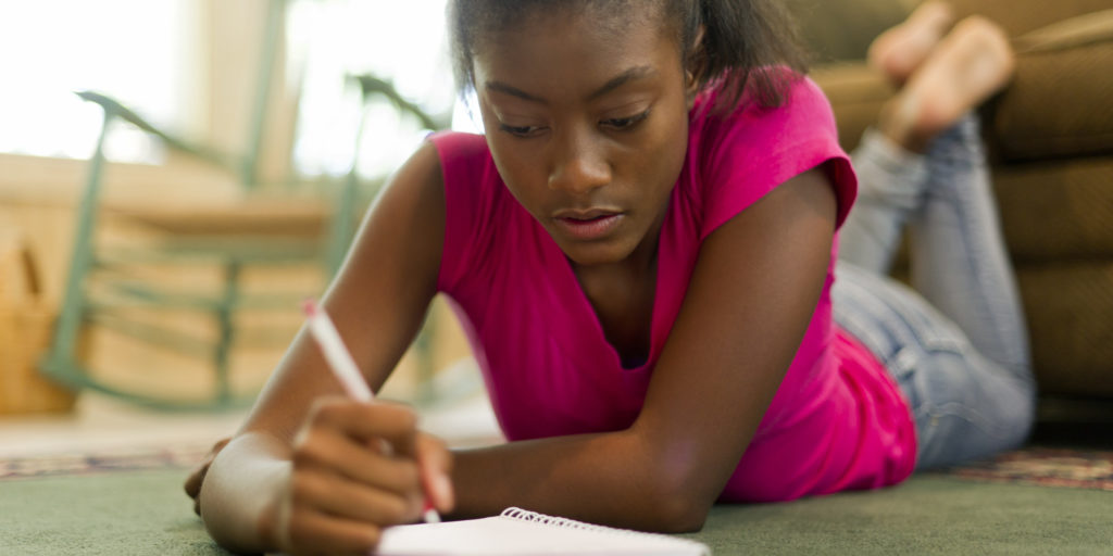 African American female teen writing in journal